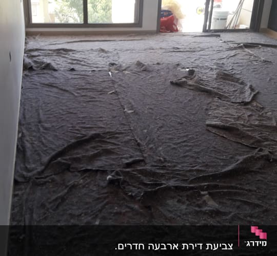 יריעות בד מכסות רצפה בחדר לקראת צביעה